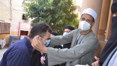بالصور... إمام مسجد ومنتقبات يوزعون كمامات ومطهرات على الاقباط